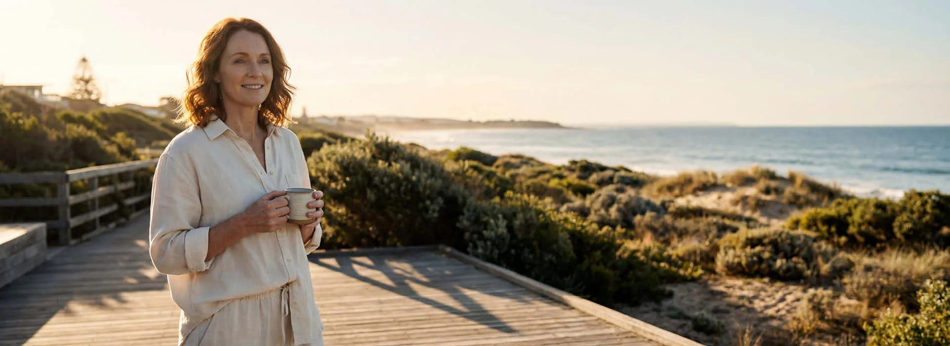 A woman enjoying a calm morning with a warm drink by the coast
