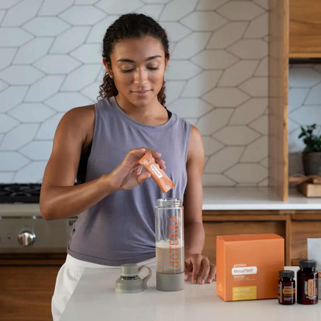dōTERRA MetaPWR Supplement – a woman preparing a dōTERRA MetaPWR drink in a modern kitchen, supporting energy, metabolism, and wellness.