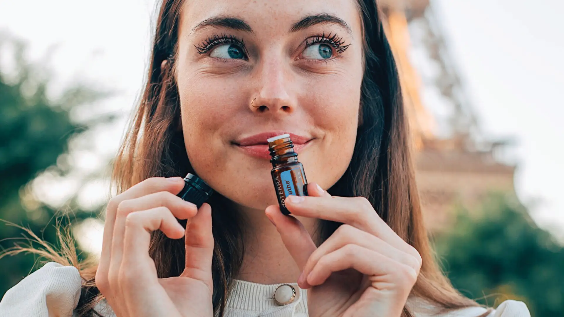 A woman inhaling dōTERRA Breathe essential oil blend for clear airways and respiratory support.