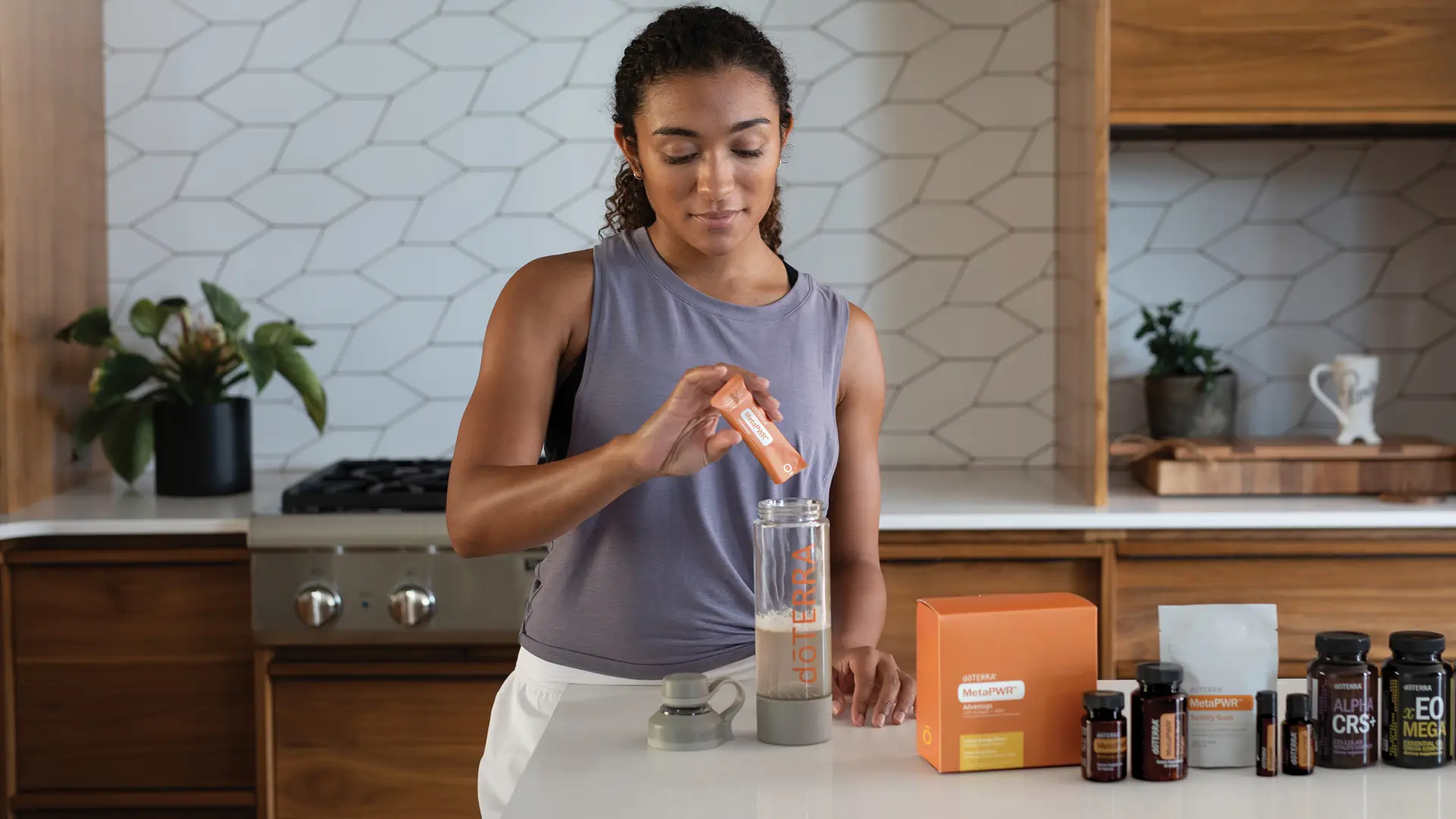 Woman in activewear preparing a drink with dōTERRA MetaPWR Advantage with Hydrolysed Collagen in her kitchen, alongside other MetaPWR products.