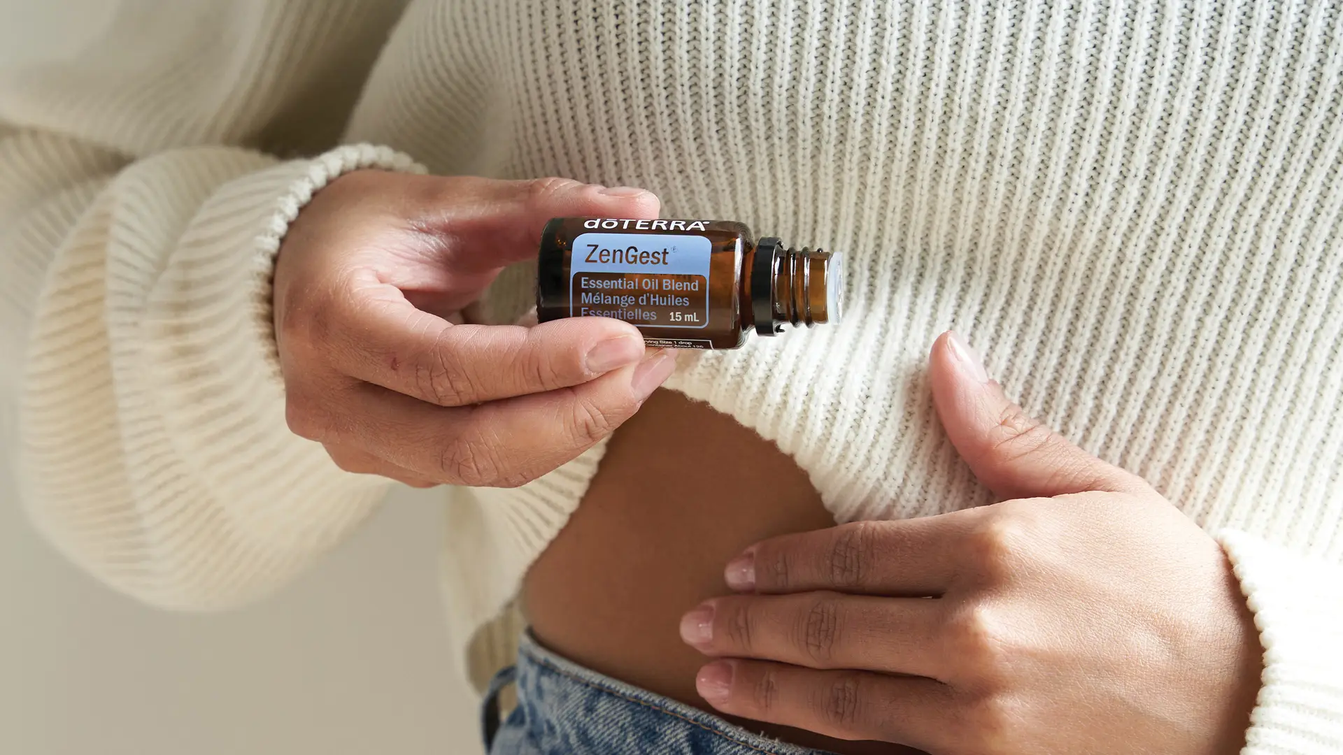 Person applying dōTERRA ZenGest to their stomach area for digestive support.